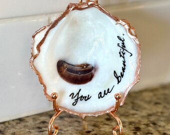 Real oyster shell, beach combed along Florida’s gulf coast with “You are beautiful” hand painted on it. Stand additional purchase.