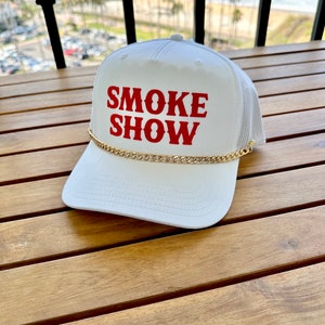 May include: White mesh trucker hat with a gold chain and red embroidered text that reads "SMOKE SHOW".