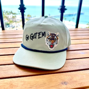 May include: A light green baseball cap with a black embroidered tiger face and the text "Go Get Em" on the front.