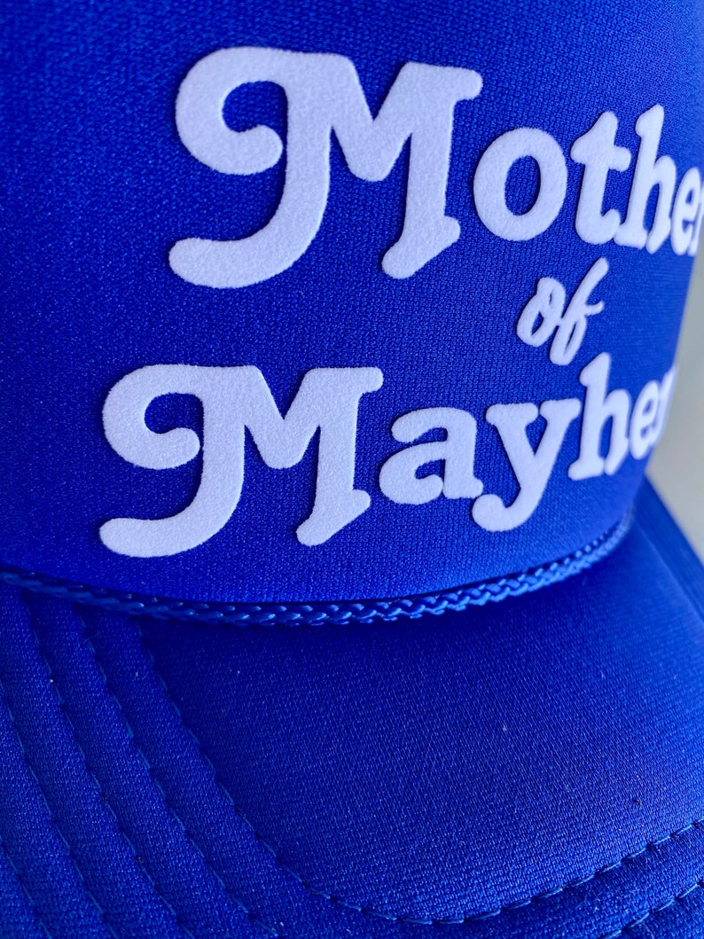 K&ouml;nnte beinhalten: Eine k&ouml;nigsblaue Trucker-Kappe mit wei&szlig; gesticktem Text, der "Mother of Mayhem" lautet.