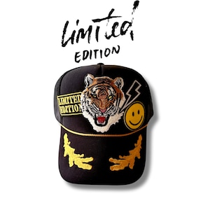 May include: Black trucker hat with a tiger face, lightning bolt, and smiley face embroidered patches. The hat also has a black and yellow "Limited Edition" patch.
