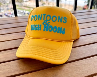 May include: A yellow trucker hat with a blue embroidered logo that says "Pontoons & High Noons".