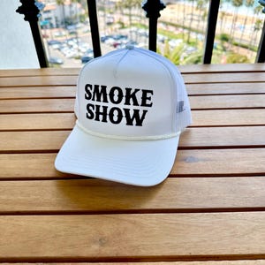 May include: White trucker hat with a black embroidered logo that says "SMOKE SHOW".