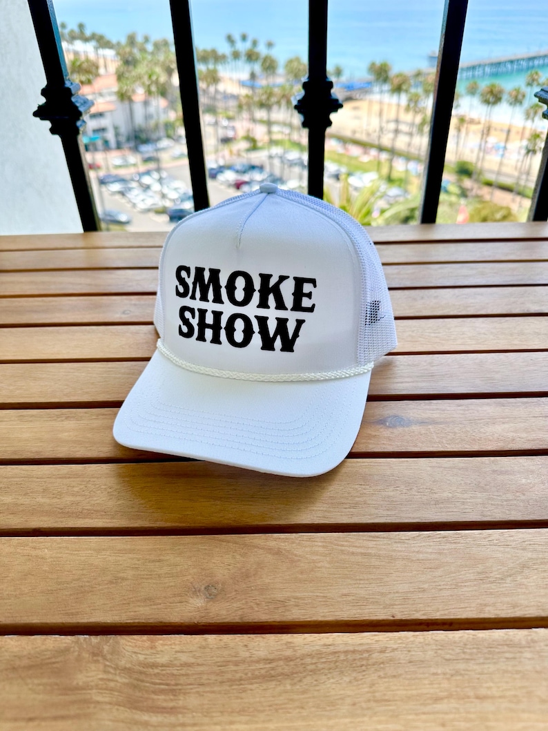 May include: White trucker hat with a black embroidered logo that says "SMOKE SHOW".
