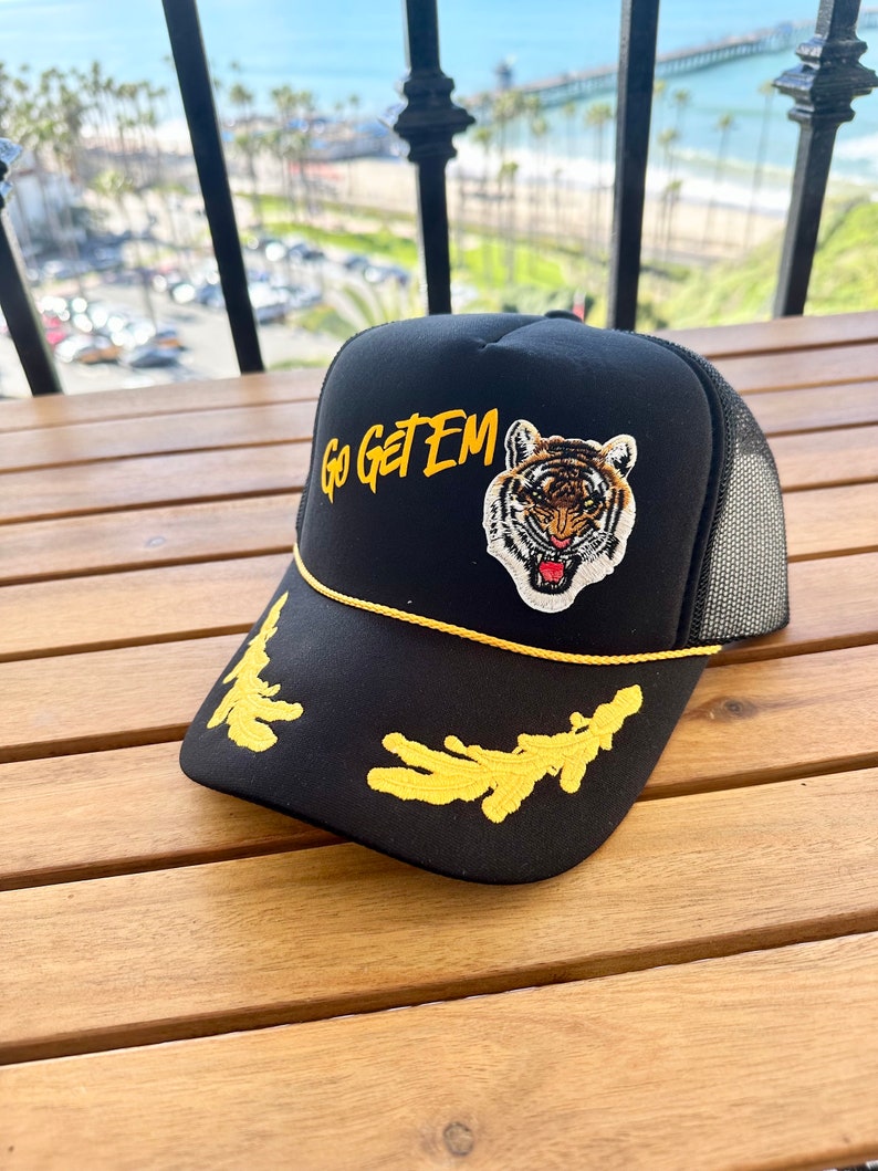 May include: Black trucker hat with a yellow embroidered tiger and the words "Go Get Em" in yellow.