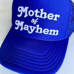 K&ouml;nnte beinhalten: Ein k&ouml;nigsblauer Trucker-Hut mit wei&szlig;em Netzr&uuml;cken. Die Vorderseite des Hutes tr&auml;gt wei&szlig;en Text mit der Aufschrift "Mother of Mayhem".