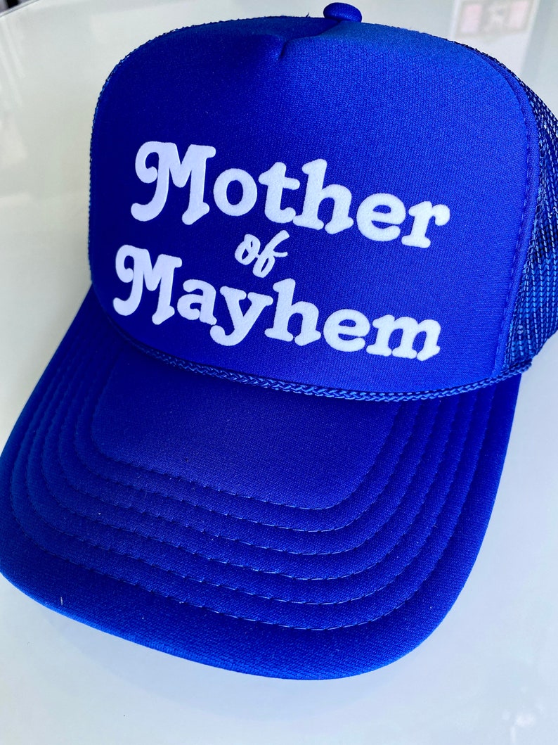 K&ouml;nnte beinhalten: Ein k&ouml;nigsblauer Trucker-Hut mit wei&szlig;em Netzr&uuml;cken. Die Vorderseite des Hutes tr&auml;gt wei&szlig;en Text mit der Aufschrift "Mother of Mayhem".