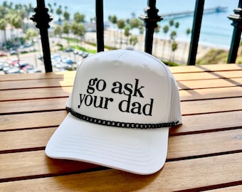 Könnte beinhalten: Weiße Trucker-Kappe mit schwarzem Kettenbesatz und dem Text "go ask your dad" in Schwarz.