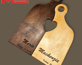 May include: Two wooden cutting boards, one dark brown and one light brown, interlock to form a heart shape. The dark brown board is engraved with the name "Mario" and the date "Married: 22.06.19". The light brown board is engraved with the name "Mackenzie" and the date "Dating: 31.10.14".