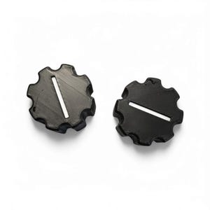 May include: Two black, gear-shaped knobs with a white, rectangular groove. The knobs are set against a white background. The gear-shaped design has rounded edges.