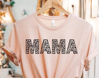 May include: A light pink t-shirt with the word "MAMA" printed in black with a leopard print pattern.