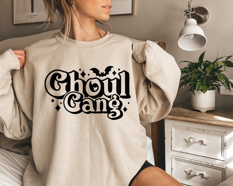 May include: A beige sweatshirt with a black graphic that says "Ghoul Gang" with a bat and stars.