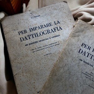 Könnte beinhalten: Zwei antike Bücher mit den Titeln "Per Imparare La Dattilografia" und "Per I Datti" auf den Einbänden. Beide Bücher enthalten 100 Übungen und sind für Berufsschulen und Privatschulen gedacht.