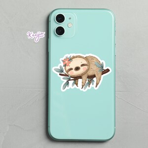 May include: A cute cartoon sloth with a pink flower on its head is sleeping on a branch with green leaves. The sloth is brown and has a white belly. The background is a light blue phone case.