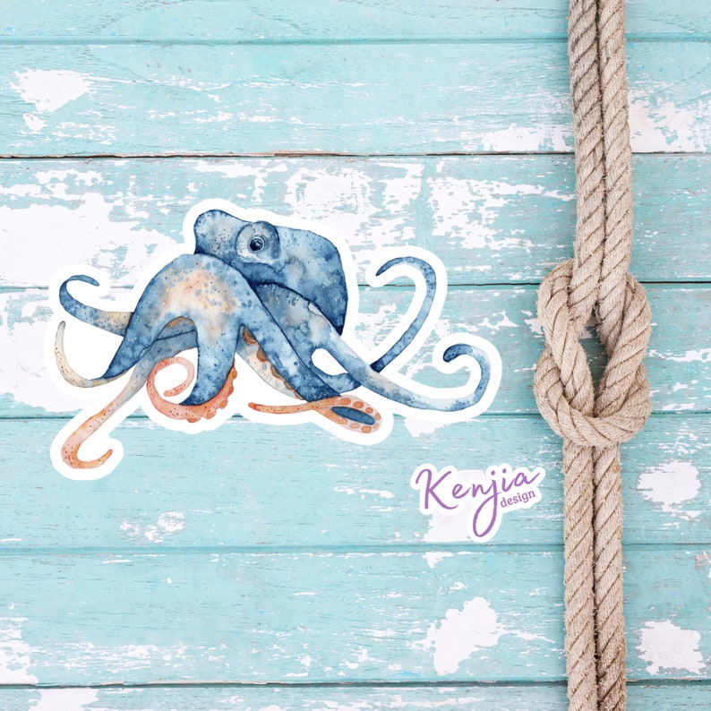May include: A blue and orange watercolor octopus illustration with a white outline. The octopus is curled up with its tentacles reaching out. The illustration is on a light blue wooden background with a brown rope in the upper right corner. The text "Kenjia Design" is in purple lettering below the octopus.