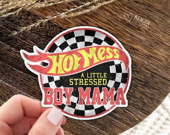 May include: A circular sticker featuring a black and white checkered pattern background. The text Hot Mess is written in yellow with a red outline, followed by the text A LITTLE STRESSED in yellow and BOY MAMA in red block letters.
