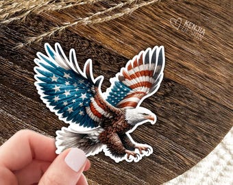 May include: A die-cut sticker featuring a bald eagle in flight with wings spread wide. The eagle's feathers are patterned with the red, white, and blue colors of the American flag, including stars on the left wing. The text KENJIA DESIGN is visible.