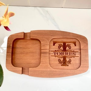 May include: A wooden serving tray with a square compartment and a larger rectangular compartment. The larger compartment has a personalised monogram with the letter "T" and the name "TORRES" engraved in the wood.