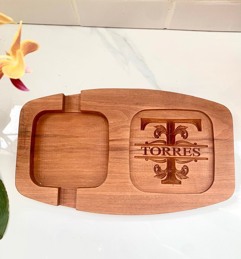 May include: A wooden serving tray with a square compartment and a larger rectangular compartment. The larger compartment has a personalised monogram with the letter "T" and the name "TORRES" engraved in the wood.