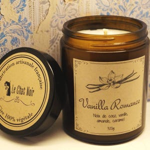 Può includere: Un barattolo di vetro marrone contenente una candela con un'etichetta che recita "Vanilla Romance" e elenca le note olfattive: "Noix de coco, vanile, amande, caramel". L'etichetta include anche il testo "Fabrication artisanale française" e "Le Chat Noir". Il barattolo di candela è di 320g.