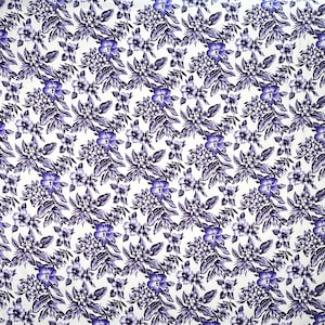 May include: A white fabric with a repeating pattern of purple flowers and leaves.