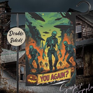 May include: Double-sided Halloween garden flag featuring a zombie-themed illustration. The artwork depicts zombies, flying saucers, and the text "YOU AGAIN?" in a vibrant, comic book style. The flag is designed for outdoor display.