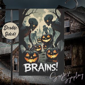 May include: Double-sided Halloween garden flag featuring a spooky scene with glowing-eyed skeletons, jack-o'-lanterns, and the word "BRAINS!" in white. The flag is designed with a dark, eerie color palette, perfect for outdoor Halloween decor.