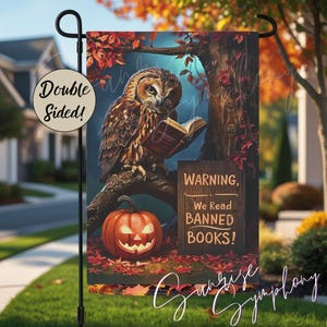 May include: Double-sided garden flag with a brown owl reading a book on a tree branch, a jack-o'-lantern, and the text "Warning, We Read Banned Books!". The flag is set against a backdrop of autumn leaves.