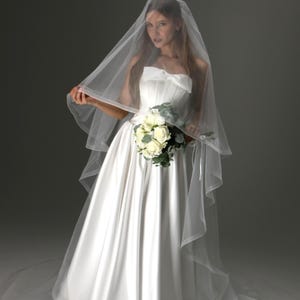 May include: A white satin wedding gown with a strapless bodice and full skirt. The bride is holding a bouquet of white roses and wearing a sheer veil. The dress has a bow detail at the bust.