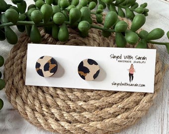 May include: A pair of round stud earrings with a leopard print design. The earrings are displayed on a white card with the text "Slayed With Sarah Handmade Jewelry" and the website "slayedwithsarah.com". The earrings are set on a woven rope surface.