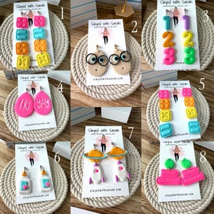 May include: Eight sets of colorful polymer clay earrings displayed on white cards. Designs include math symbols, googly-eyed faces with glasses, numbers, the text FRI YAY, glue bottles, rockets with planets, and stacked books in various bright colors.