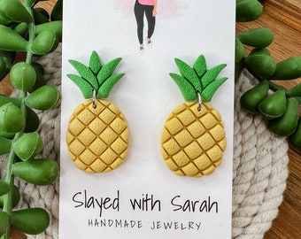 May include: A pair of yellow and green pineapple earrings on a white card with the text "Slayed with Sarah Handmade Jewelry".