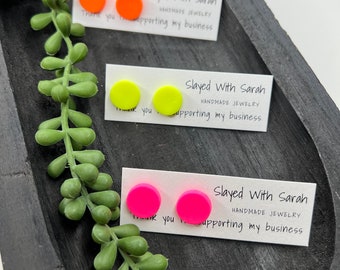 May include: Three pairs of brightly colored stud earrings in orange, neon yellow, and hot pink. Each pair is displayed on a small white card with the text "Slayed With Sarah HANDMADE JEWELRY Thank you for supporting my business."