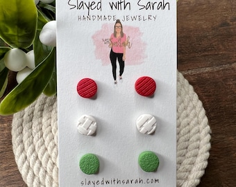 May include: A card with six pairs of handmade stud earrings in red, white, and green. The card reads "Slayed with Sarah Handmade Jewelry" and includes the website address. The earrings have textured designs.