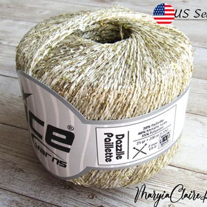 May include: A skein of gold yarn with metallic accents. The yarn is labeled "Dazzle Paillette" and is made of 20% Paillette, 40% Metallic Lurex, and 35% Polyester. The skein weighs 25 grams and is 200 meters long.