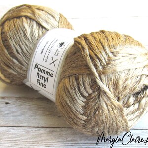May include: A ball of Flamme Acryl Fine yarn in a light brown and white colorway. The label reads "100% Acrylic, 50 gr, 220 m, 3 mm, US 3, Flamme Acryl Fine".