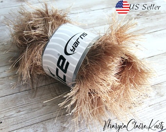 May include: A skein of light brown fluffy yarn with a white label that says "Ice Yarns" on it. The yarn is on a wooden surface.