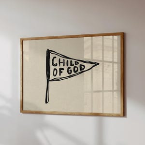 Può includere: Una stampa artistica incorniciata con un disegno di bandiera disegnato a mano. La bandiera bianca ha un testo nero che recita "CHILD OF GOD". L'opera d'arte è ambientata su uno sfondo neutro e incorniciata in una cornice di legno chiaro.