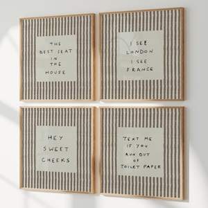May include: A set of four square wall art prints in light wood frames, each featuring a grey and white vertical striped background with a central pale green square containing black handwritten text: THE BEST SEAT IN THE HOUSE, I SEE LONDON I SEE FRANCE, HEY SWEET CHEEKS, and TEXT ME IF YOU RUN OUT OF TOILET PAPER.