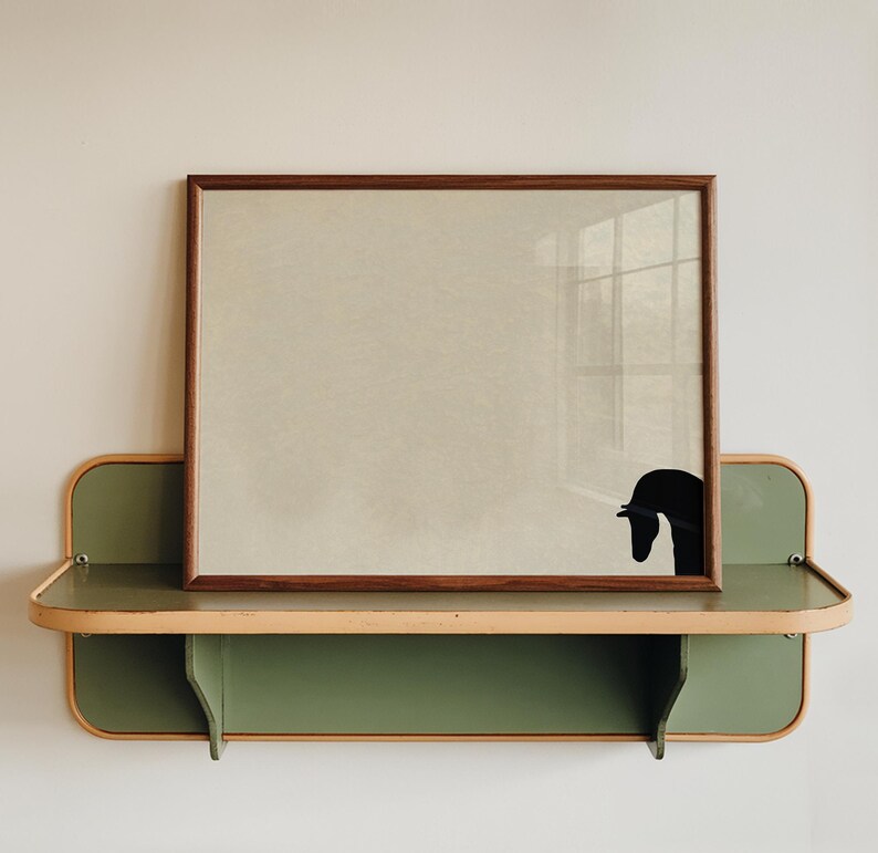 May include: A framed artwork with a brown wooden frame, featuring a black silhouette of a swan. The artwork rests on a green and tan shelf with a curved design, mounted on a white wall. The shelf has a lower shelf.