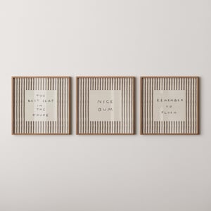 May include: Three square wall art prints in light wood frames featuring a vertical gray and white striped pattern. Each print contains a centered cream-colored square with black handwritten text reading THE BEST SEAT IN THE HOUSE, NICE BUM, and REMEMBER TO FLUSH.