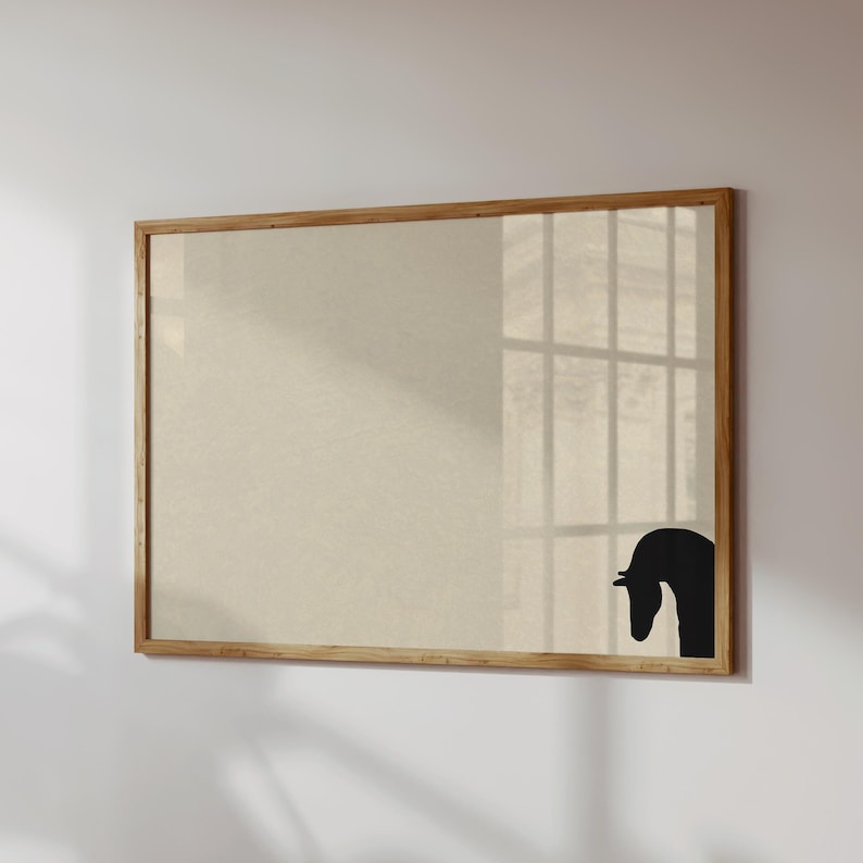 May include: A rectangular framed artwork featuring a beige background with a black horse head silhouette in the lower right corner. The frame is made of light-colored wood. The artwork is mounted on a white wall.