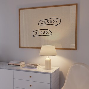 May include: A framed artwork with the text "JESUS?" above "JESUS." in black speech bubbles. The artwork hangs above a white cabinet with a lamp and books. The cabinet has a marble tile top and gold knobs.