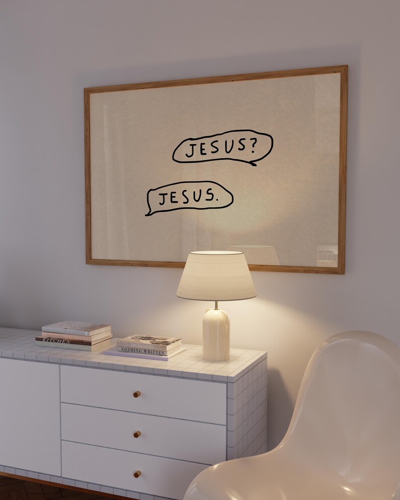 May include: A framed artwork with the text "JESUS?" above "JESUS." in black speech bubbles. The artwork hangs above a white cabinet with a lamp and books. The cabinet has a marble tile top and gold knobs.