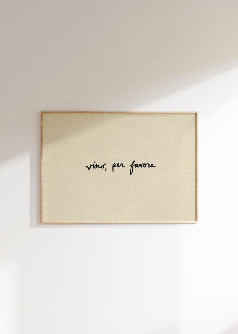 May include: A framed rectangular print with the words "vino, per favore" in black script on a beige background. The frame is a light brown color, and the print is hanging on a white wall.