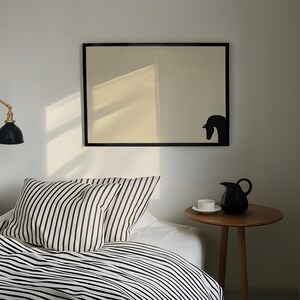 May include: A bedroom scene featuring a bed with black and white striped bedding and pillows. A black framed artwork with a horse silhouette hangs above the bed. A small wooden side table holds a black pitcher and a white teacup.