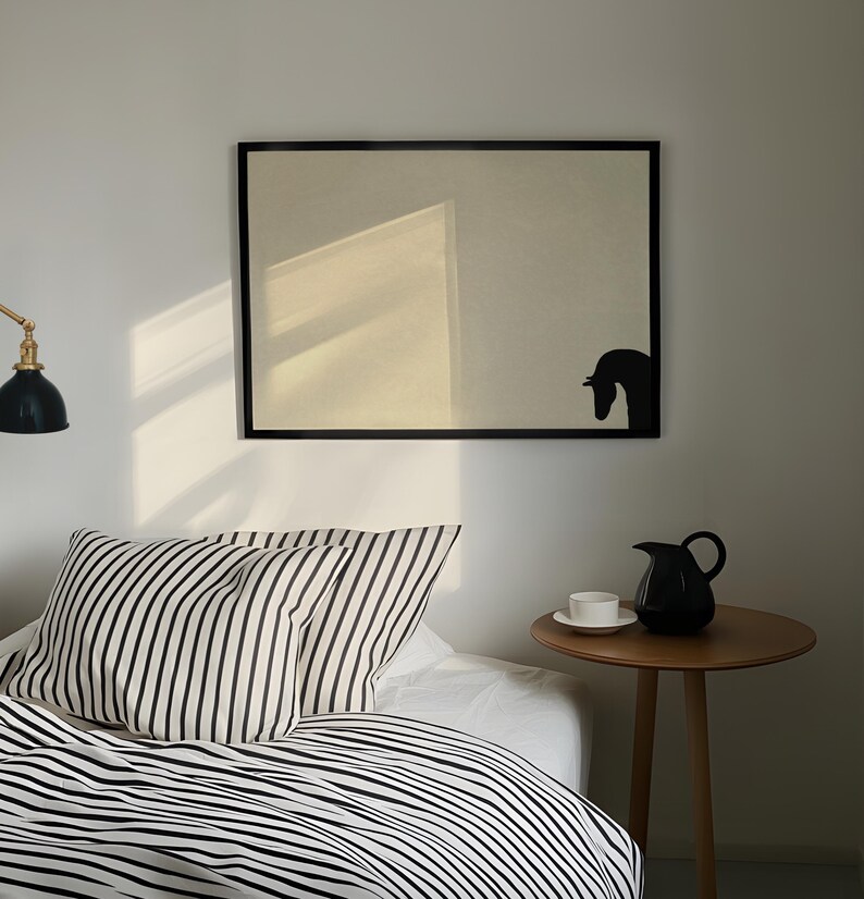 May include: A bedroom scene featuring a bed with black and white striped bedding and pillows. A black framed artwork with a horse silhouette hangs above the bed. A small wooden side table holds a black pitcher and a white teacup.