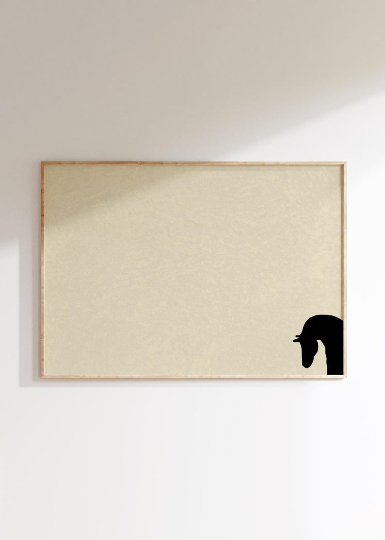 May include: A framed art print featuring a minimalist design. The artwork showcases a black silhouette of a horse's head in the lower right corner against a beige background. The frame is made of light-colored wood.