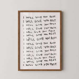 May include: A framed wall art print featuring a white background with the phrase I WILL GIVE YOU REST written in black, hand-drawn capital letters repeated fourteen times in vertical rows within a simple brown wooden frame.