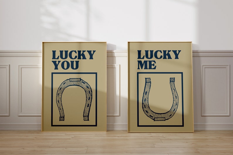 Puede incluir: Dos impresiones enmarcadas con fondo beige y contornos negros. La impresi&oacute;n de la izquierda dice "Lucky You" y la impresi&oacute;n de la derecha dice "Lucky Me". Ambas impresiones presentan una ilustraci&oacute;n de herradura en blanco y negro.